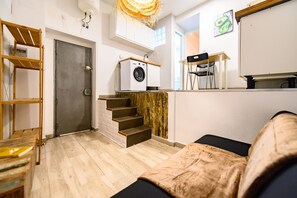Ein kompakter Wohnbereich mit Waschmaschine, Treppe, Essbereich und einem Bett.