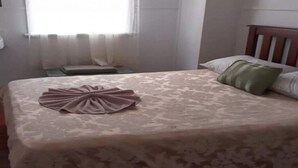 Un lit bien fait, avec une couvre-lit à motifs et une serviette pliée posée sur le dessus.