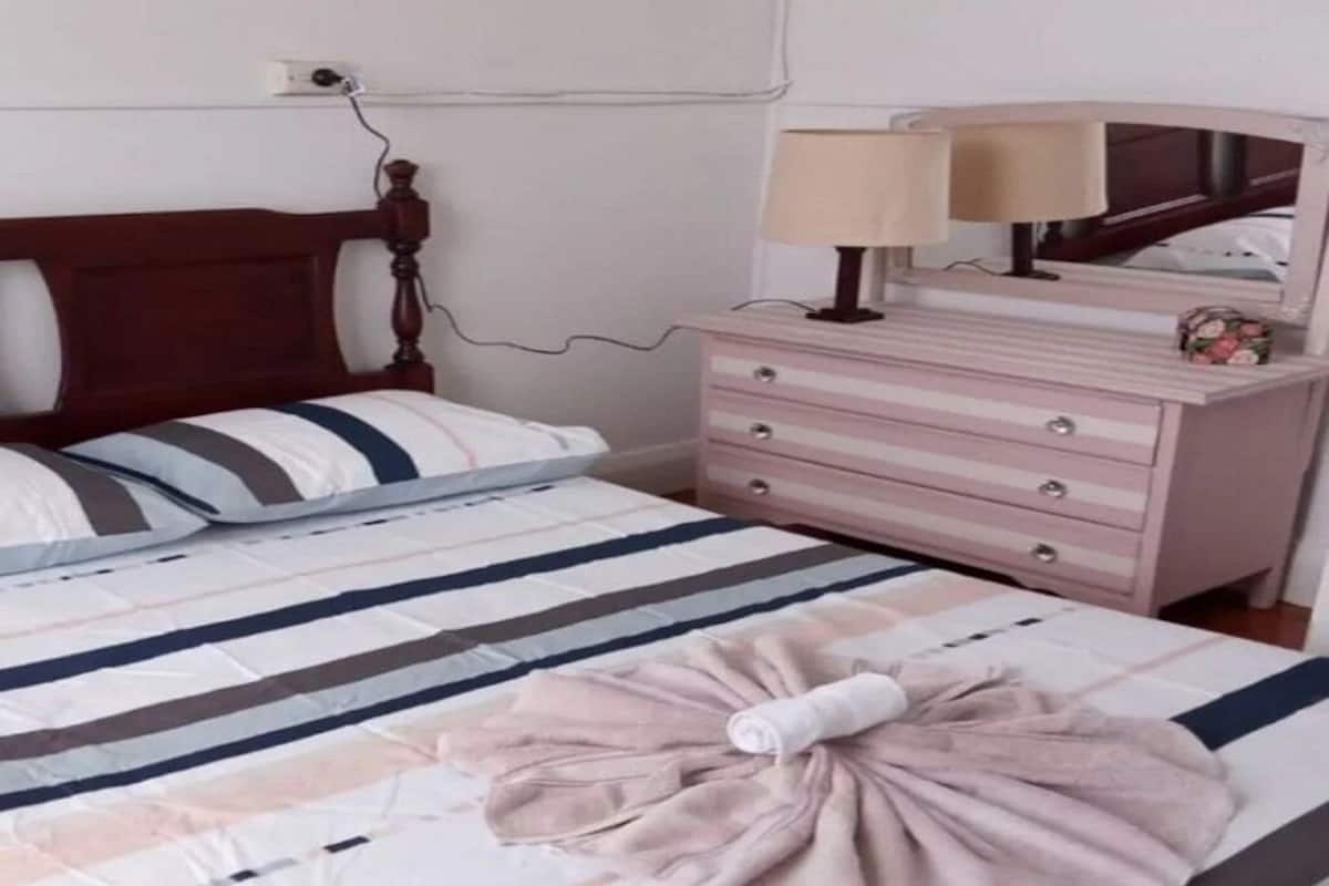 Un dormitorio con cama, cómoda, espejo y lámpara.