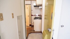 A narrow hallway leading to a kitchen with a sink, cabinets, and a microwave. - Compact Easy Stay - Budget Nakasu (Fukuoka)