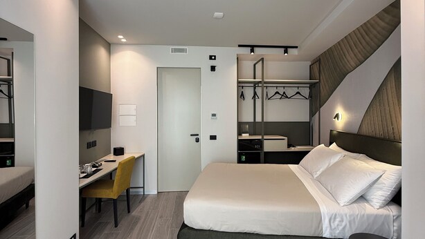 Una habitación de hotel moderna con cama, escritorio, silla y una pequeña mesa.