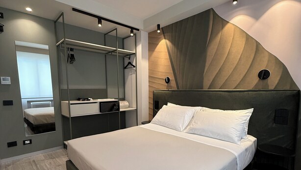 Une chambre à coucher moderne avec un lit, une armoire intégrée, un miroir et un décor mural original.