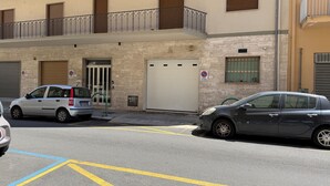 Un bâtiment doté d’une porte de garage, d’un balcon avec des garde-corps en métal et d’un panneau indiquant qu’il est interdit de se garer.