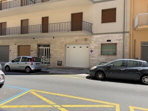 A building with a garage door, a balcony with metal railings, and a no parking sign. - WakeApp Tech B&B (Reggio Calabria)