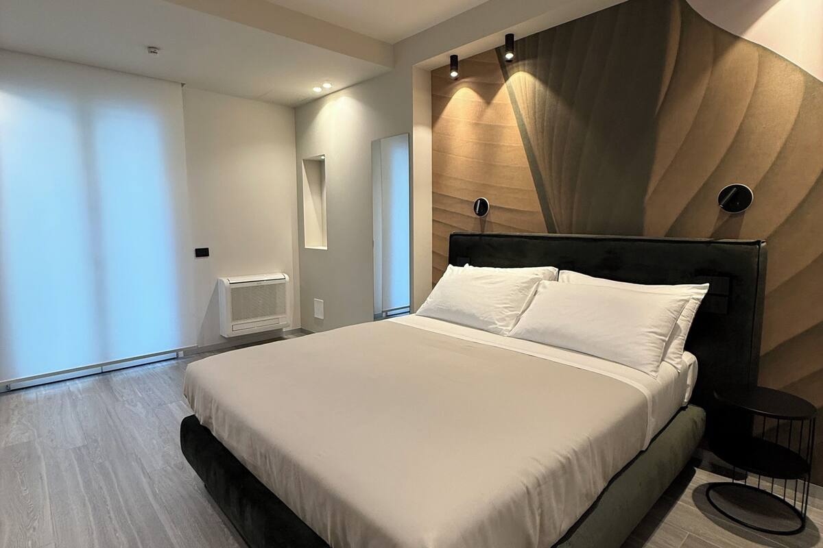 Un dormitorio moderno con una cama grande, un panel de madera decorativo y una mesita de noche pequeña.