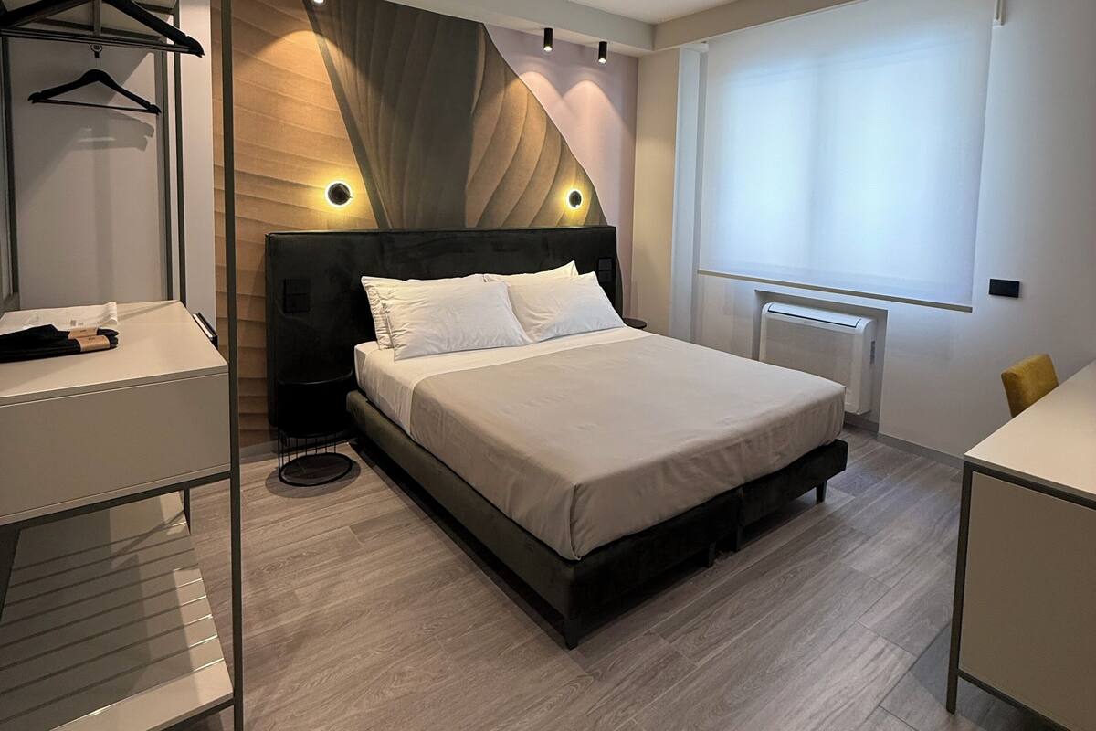 Un dormitorio moderno con cama, mesitas de noche, armario y ventana con persianas.
