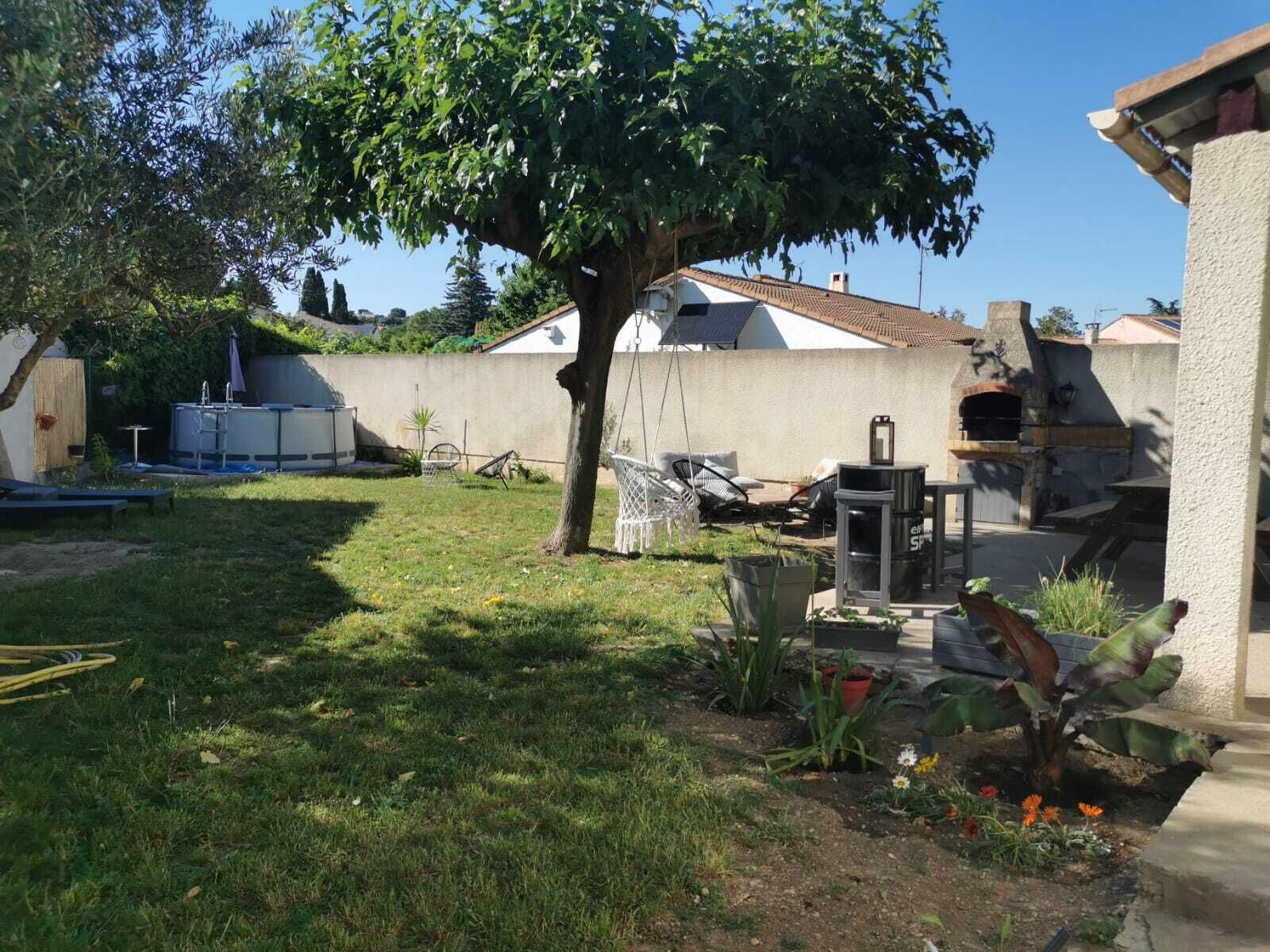 Un pati amb un arbre, mobles d'exterior, una barbacoa i un dipòsit d'aigua.