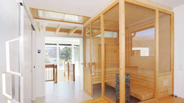 Ein modernes Interieur mit einer Holzzu sauna, einer Glastür zu einem Außenbereich und einem Holzboden.