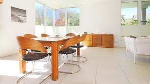 Ein moderner Essbereich mit Holztisch und -stühlen, großen Fenstern und Blick auf Bäume.