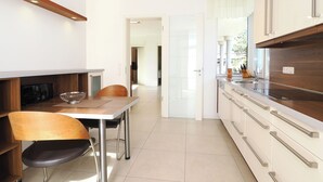 Eine moderne Küche mit Essbereich, ausgestattet mit einem Holztisch, Stühlen und einem eingebauten Backofen.