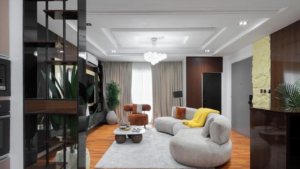 Una sala de estar moderna con un sofá seccional gris, una mesa de centro y una planta grande.