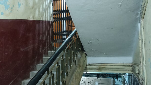 A staircase with a metal railing, a partially painted wall, and a metal mesh window. - Balaji Guest House (Guwahati)