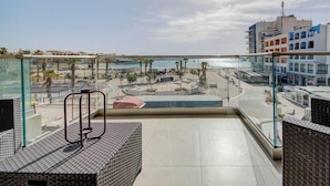 A balcony with a view of a beach and buildings. - Beautiful 2BR seafront home with WIFI & comfy beds (Birżebbuġa)