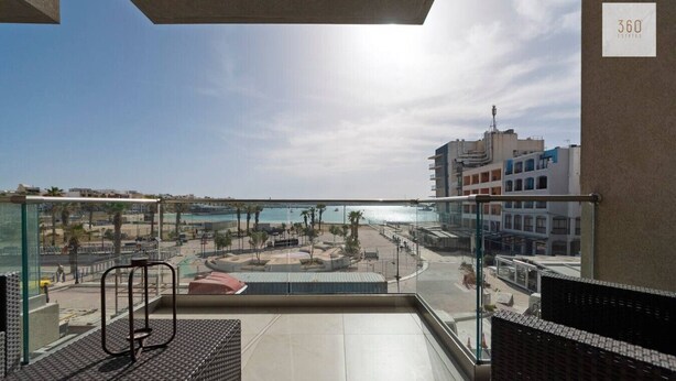 A balcony with a view of a beach and buildings. - Beautiful 2BR seafront home with WIFI & comfy beds (Birżebbuġa)
