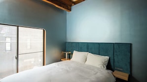 A bedroom with a bed, a nightstand, a window, and a wall with a textured finish. - MU HEN KO Tokyo (Tokyo)