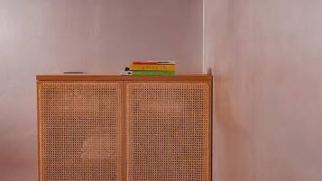Un mueble de madera con panel frontal tejido y una pila de libros encima.