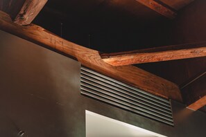 A ceiling with exposed wooden beams and a metal vent.