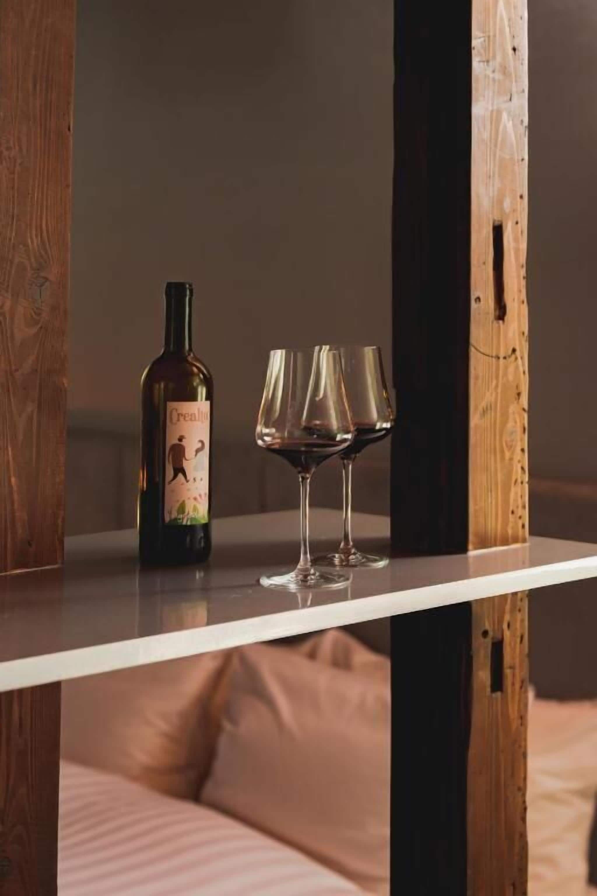 Una botella de vino y dos copas sobre una mesa de madera.