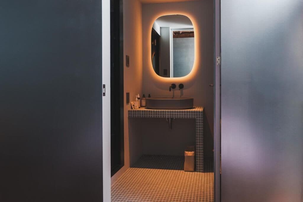 A bathroom with a tiled floor, a sink with a mirror, and a towel rack.