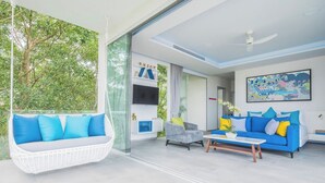 Uma sala de estar moderna com uma cadeira suspensa, um sofá azul e uma mesa de centro.