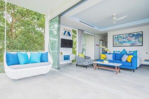 A modern living room with a hanging chair, a blue sofa, and a coffee table. - Villa Enjoy - Modern Luxury  in Patong (Tambon Patong)