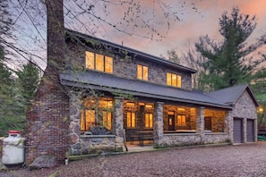 Ein zweistöckiges Steinhaus mit überdachter Veranda und Garage.