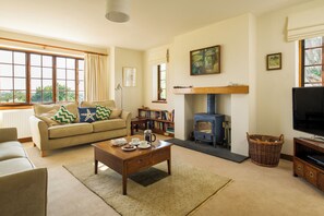 Ein Wohnzimmer mit Sofa, Couchtisch, Kamin, Fernseher und Bücherregal.