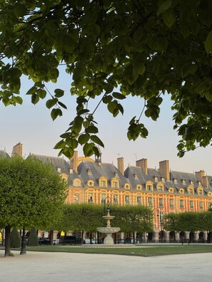 Un bâtiment historique à la façade symétrique, doté d’une fontaine centrale et d’une cour dallée.
