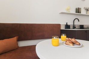 Una cocina moderna con encimera blanca, grifo negro y estante blanco decorado con objetos.