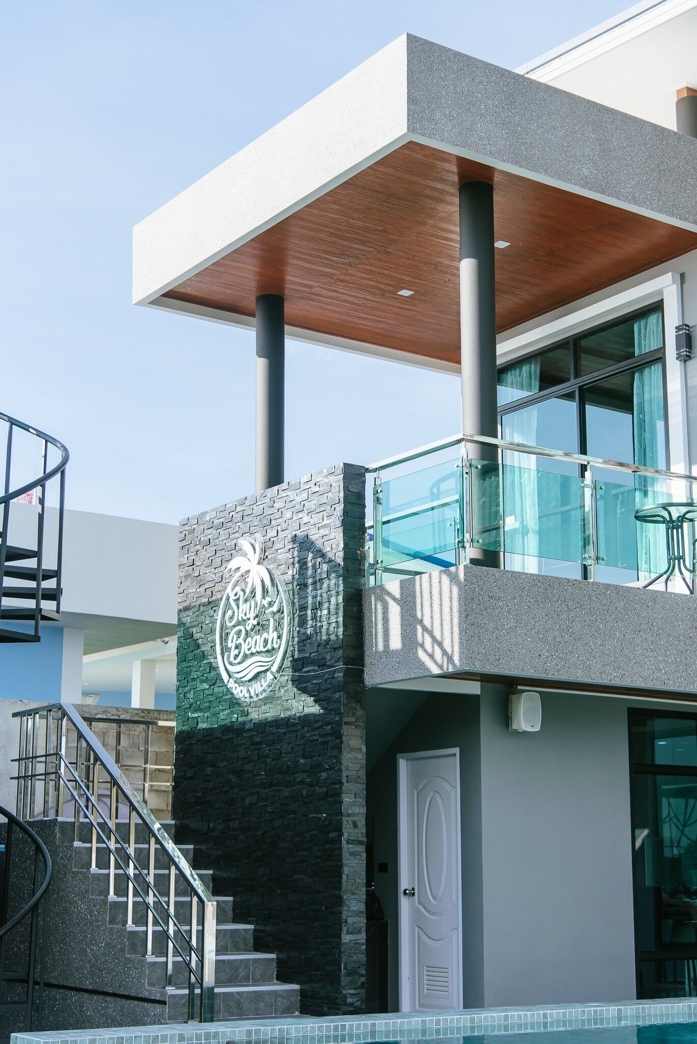 Un edificio moderno con un letrero que dice 'Sky Beach' y un balcón de vidrio.