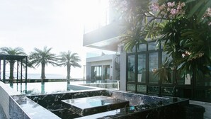 A modern infinity pool with a marble design, surrounded by palm trees and a view of the sea.