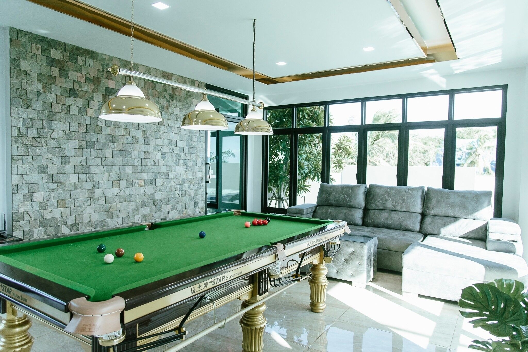 A pool table with balls, a sofa, and a large window with a view.