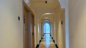 A long, narrow hallway with a patterned floor, white walls, and an arched ceiling. - Hotel The Edge (Huzur)