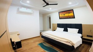 A modern bedroom with a bed, ceiling fan, recessed lighting, and a painting on the wall. - Hotel The Edge (Huzur)