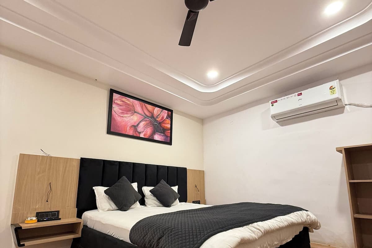 Un dormitorio moderno con cama, ventilador de techo, aire acondicionado y piso de madera.