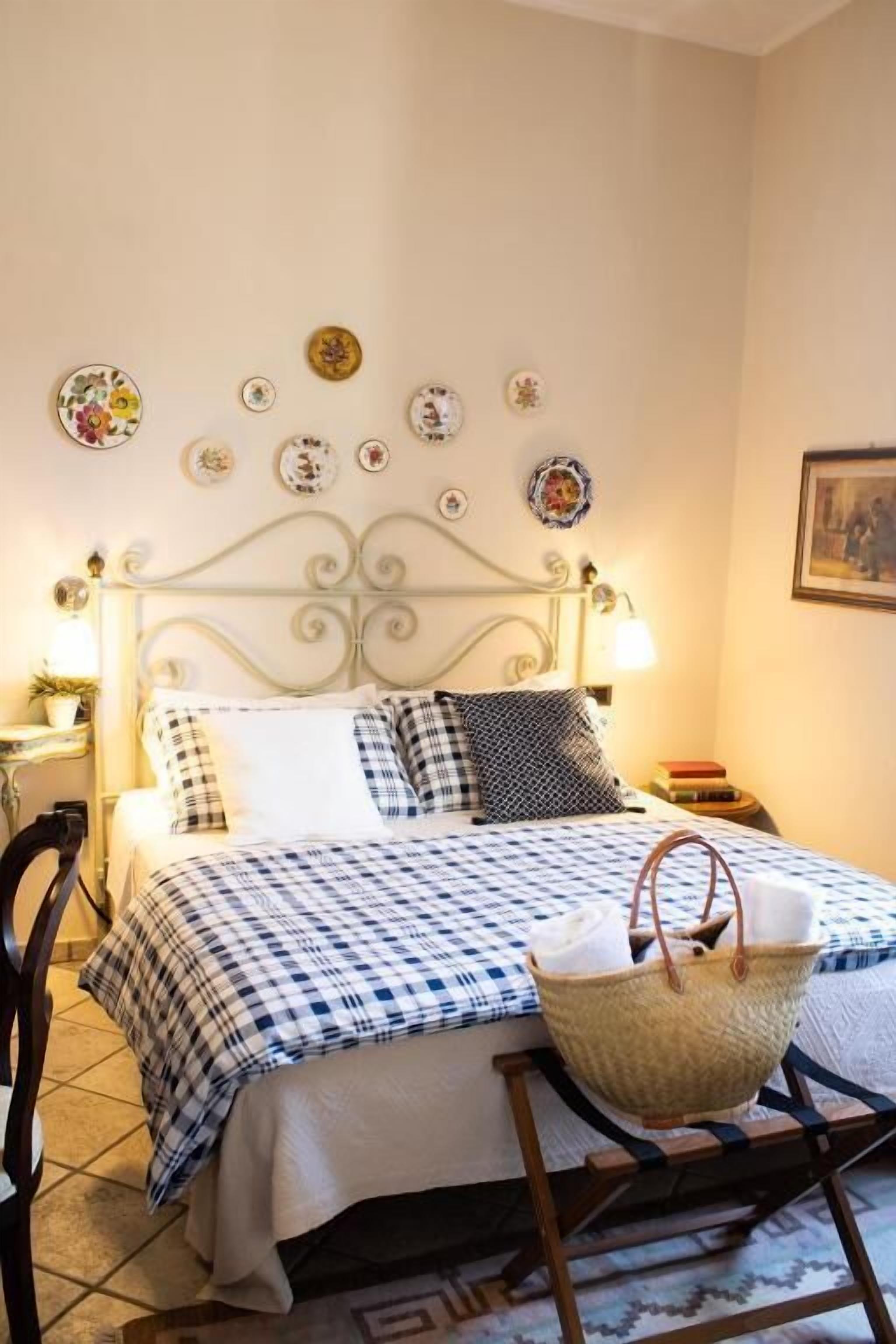 Un letto con copriletto a quadretti, un cesto in vimini e piatti appesi al muro.