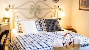Un letto con copriletto a quadretti, un cesto in vimini e piatti appesi al muro.