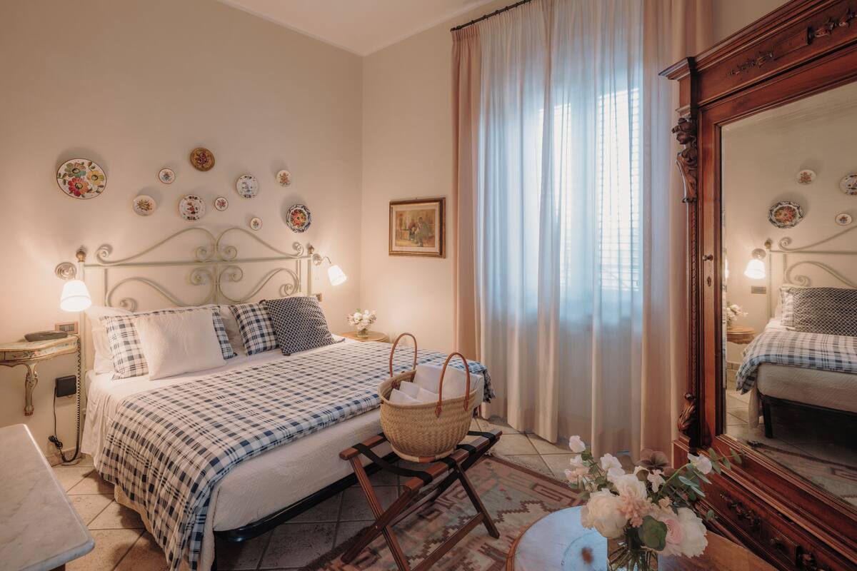 A bedroom with a bed, bedside tables, a mirror, and a wall with decorative plates.