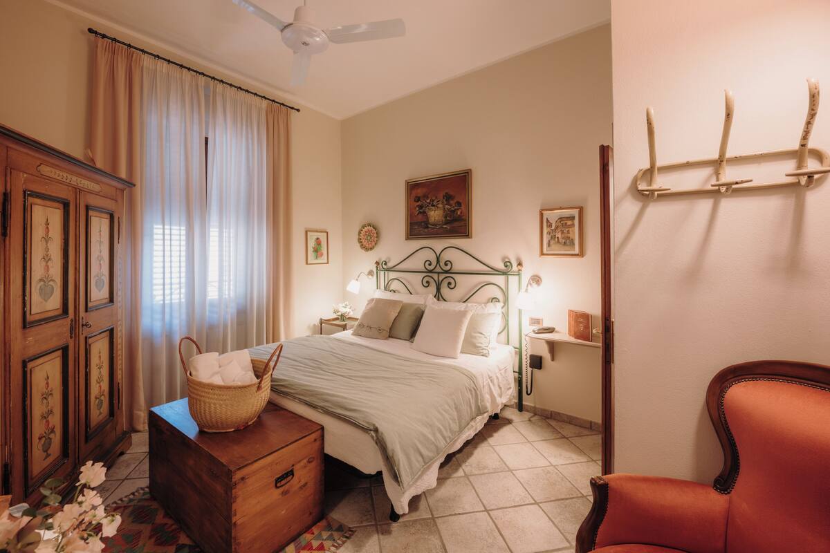 A bedroom with a bed, dresser, chair, and a ceiling fan.