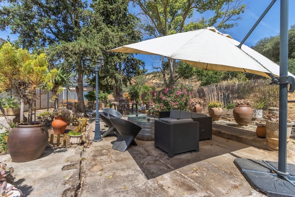 An outdoor patio area with a seating arrangement, a large umbrella, and potted plants.