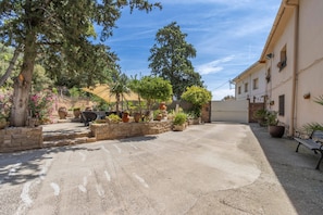 A courtyard with stone walls, potted plants, and a bench.