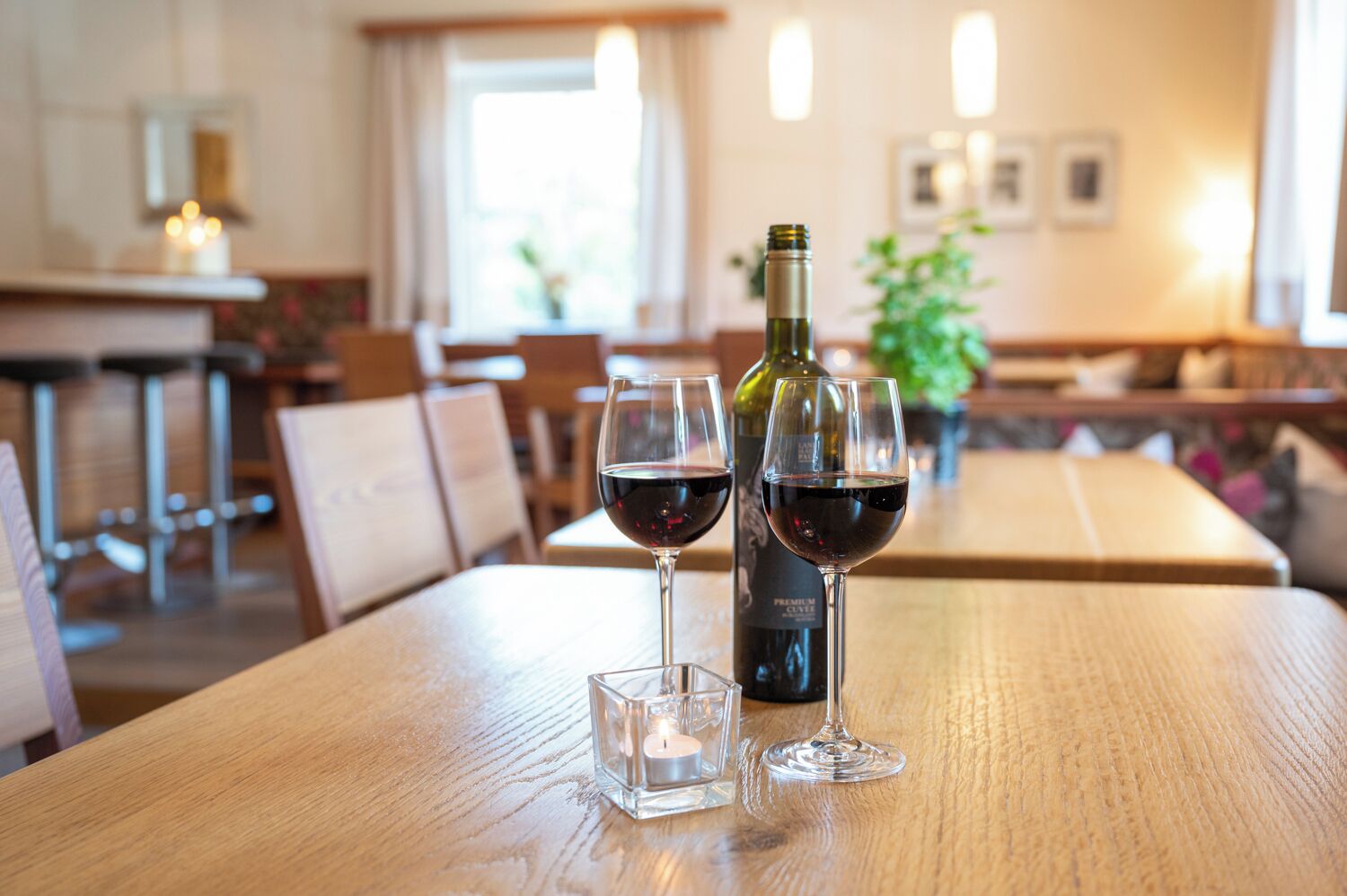 Un ambiente de restaurante con una mesa de madera, dos copas de vino y una botella.