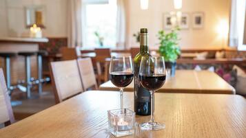 Un ambiente de restaurante con una mesa de madera, dos copas de vino y una botella.