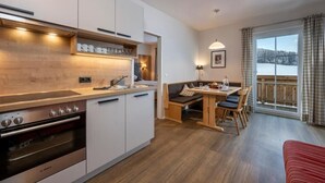 Una cocina moderna con electrodomésticos integrados, un comedor con banco y un amplio ventanal con vistas.
