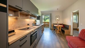 Una cocina moderna con encimeras de madera, un comedor con mesa y sillas, y un sofá rojo.