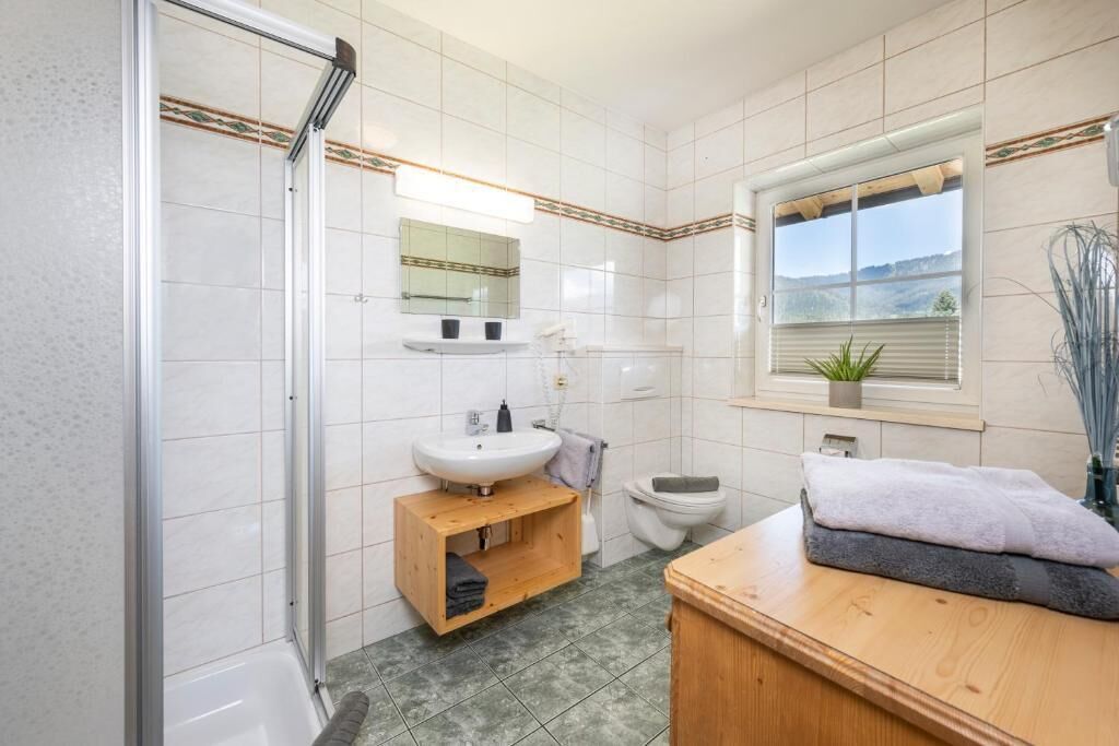 Baño con ducha, lavamanos, inodoro y ventana con vistas.