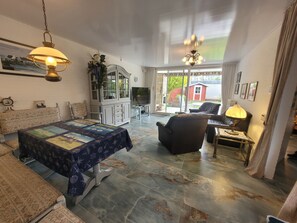 A spacious living room with a large bed, a dining table, and a seating area. - Vacation home SÜDWIND for 4 people near the beach and North Sea in Butjadingen-Tossens (Butjadingen-Tossens)