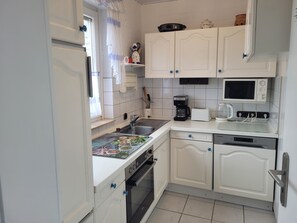 A kitchen with white cabinets, a microwave, a coffee maker, and a toaster. - Vacation home SÜDWIND for 4 people near the beach and North Sea in Butjadingen-Tossens (Butjadingen-Tossens)