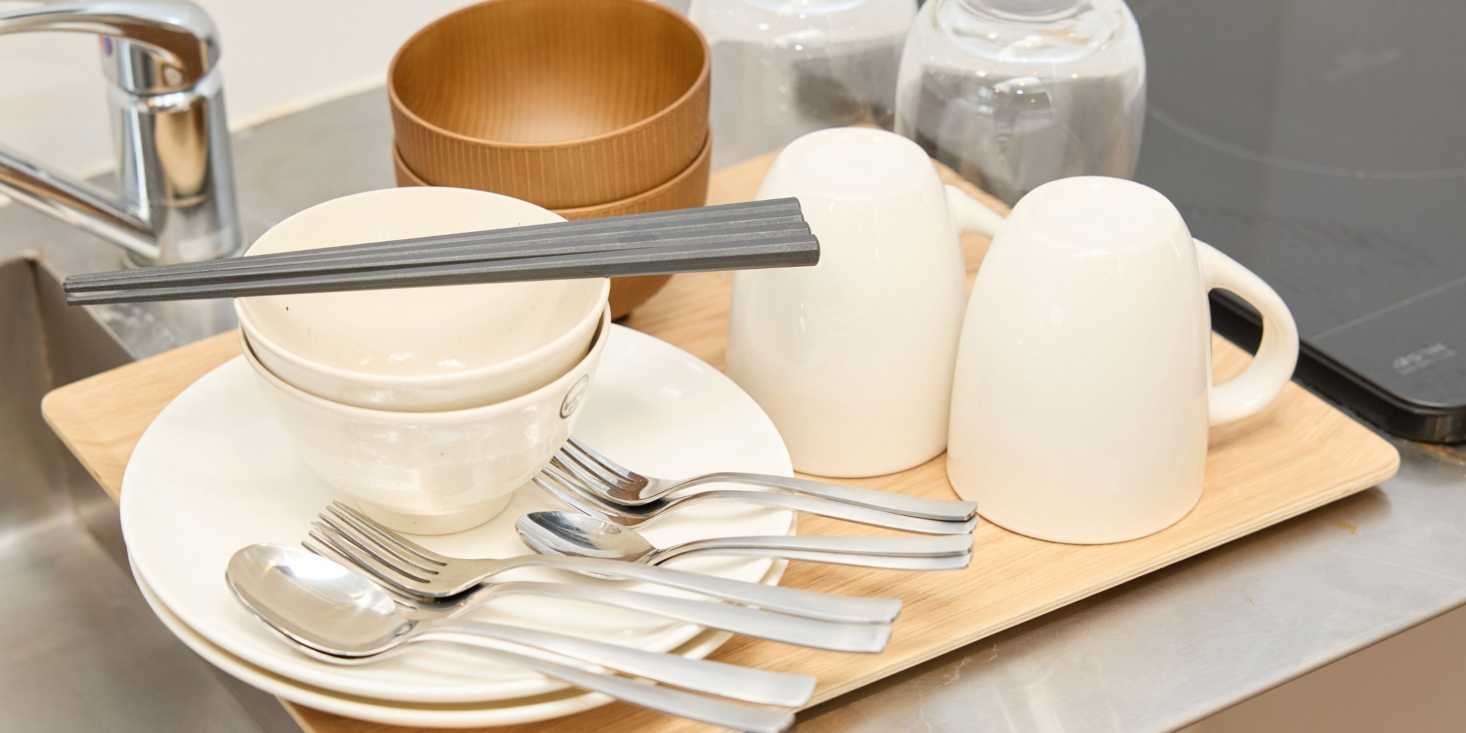 Une table dressée avec un bol, des baguettes, des cuillères et une tasse, le tout posé sur une planche en bois.