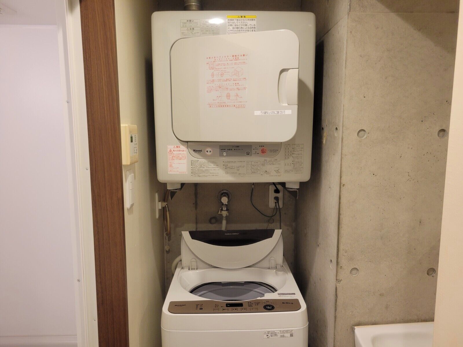 Ein kleines Badezimmer mit Toilette, Waschmaschine und Warmwasserbereiter.